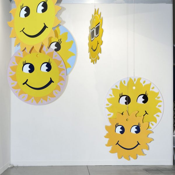 several brightly coloured hanging discs with smiley faces, based on common car air freshener designs