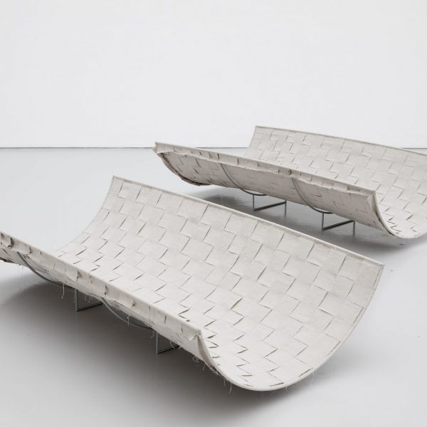 two woven fabric and steel structures on the floor, loosely resembling benches