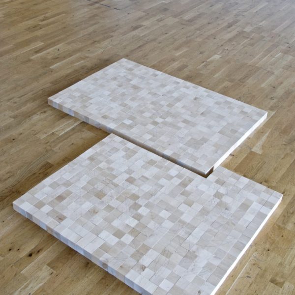 a floor based sculpture made of 2 interlocked squares comprising small wooden bricks